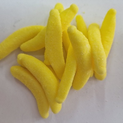 Doces amarelos em forma de banana sobre superfície branca