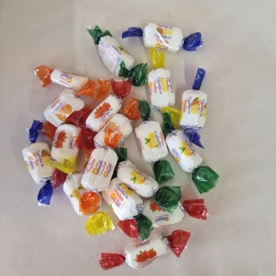 Rebuçados embalados individualmente com papel branco e colorido com imagens de frutas