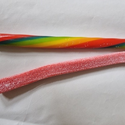 Dois bastões coloridos de doces, um em espiral e outro rosa com açúcar