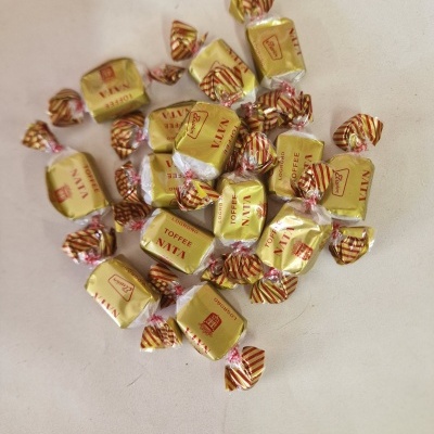 Doces Toffee embalados individualmente em papel dourado com fita listrada