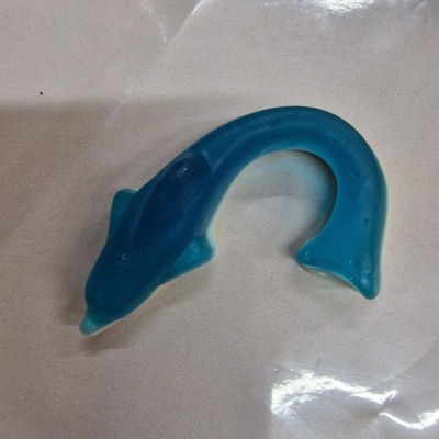 Brinquedo em forma de peixe azul sobre fundo branco com plástico transparente