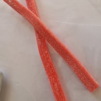 Dois tiras de doce vermelho com açúcar num fundo branco