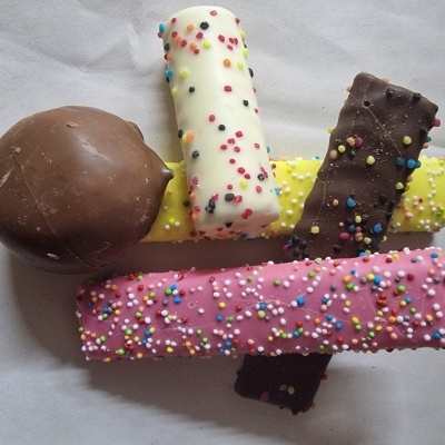 Barras de chocolate coloridas com granulados sobre fundo branco