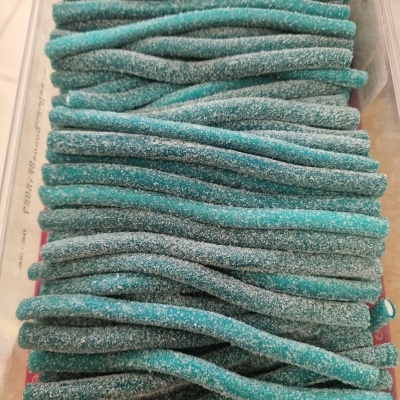 Bastões de doce azul com polvilho branco em caixa transparente