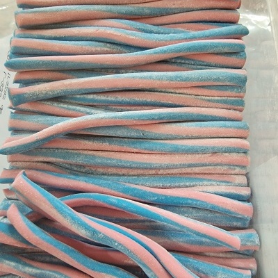 Tiras doces retorcidas rosa e azul claro com açúcar numa caixa de plástico