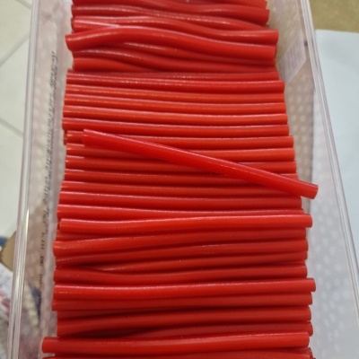 Bastões vermelhos finos em recipiente transparente com rótulo Fini Rellenitos Fresa