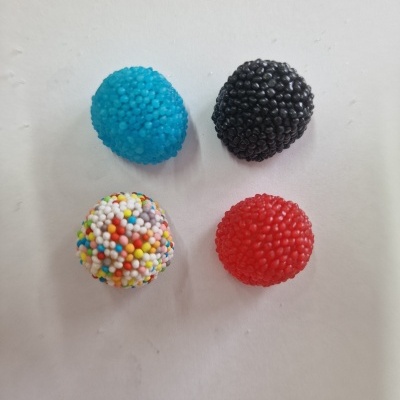 Quatro doces coloridos com textura de esferas, em azul, preto, vermelho e branco multicolorido