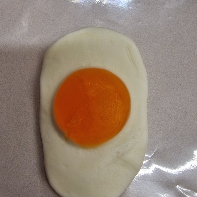 Ovo estrelado artificial com clara branca e gema laranja em fundo brilhante