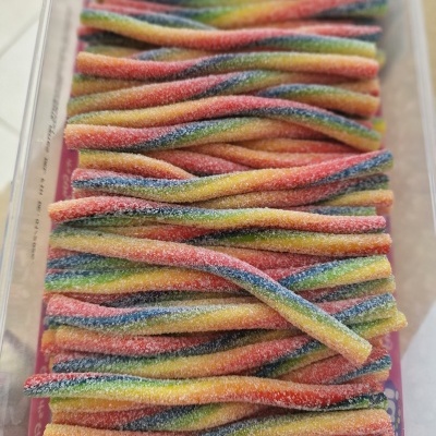 Tiras de bala de goma coloridas cobertas de açúcar numa embalagem transparente