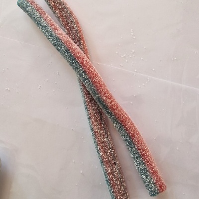 Dois doces compridos cobertos de açúcar com cores verde e vermelho.