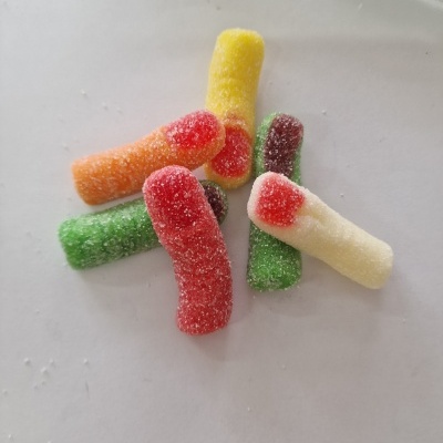 Gomas açucaradas coloridas em forma de vermes sobre superfície branca