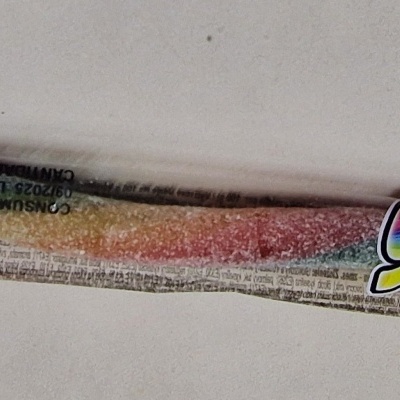 Pacote plástico transparente com doce granulado colorido e rótulo com texto 'Smoke mill' e 'Fini'