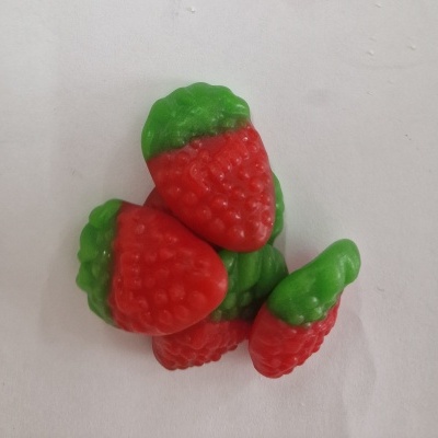 Gomas em forma de morango vermelho com verde sobre fundo branco