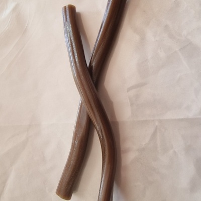 Dois tubos castanhos brilhantes cruzados sobre superfície branca