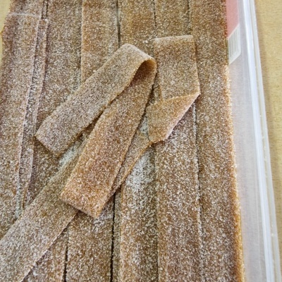 Tiras de doce castanho claro cobertas de açúcar em caixa plástica