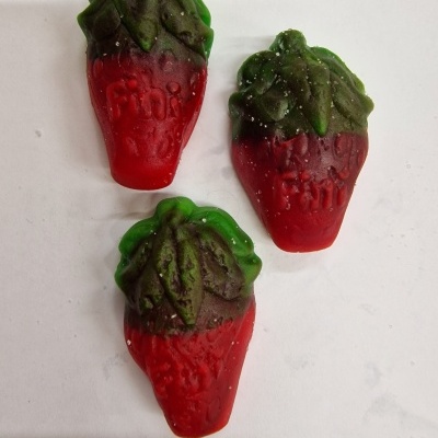 Três gomas vermelhas e verdes em forma de morango com texto em relevo