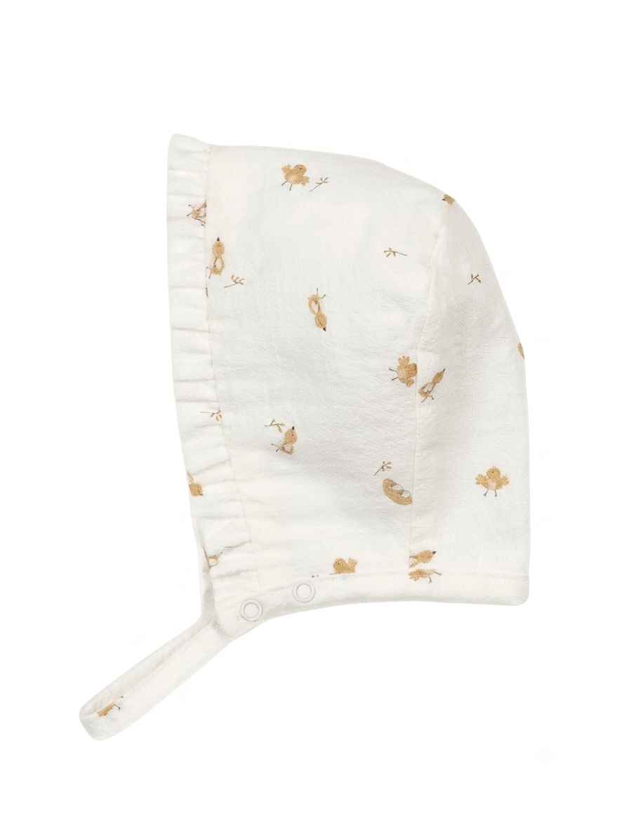Touca de algodão com folho pérola da Mighty Love - Coleção Cacau Gorro de bebé branco com padrão de pássaros castanhos e aba franzida