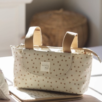 Bolsa de tecido creme com corações castanhos e alças castanhas em ambiente iluminado