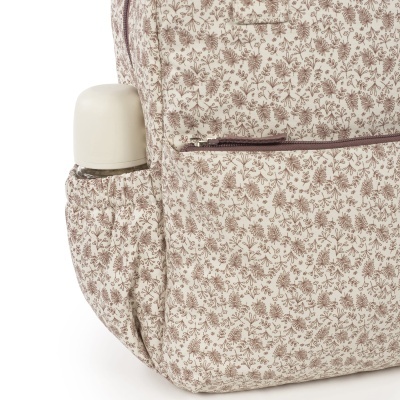 Detalhe de mochila bege com padrão floral castanho e bolso lateral com garrafa branca