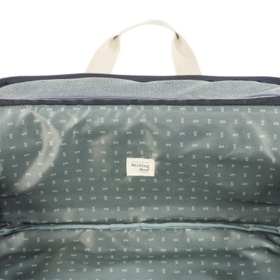 Interior de mala ou mochila azul-acinzentada com estampa de letras pequenas e etiqueta 'Walking Muse'