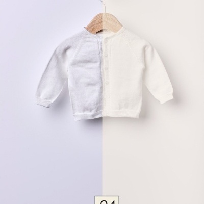 Casaco branco de bebé pendurado em cabide de madeira com fundo simples