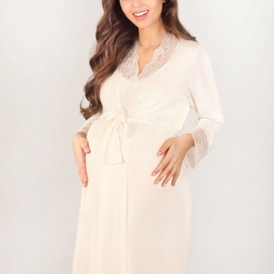 Mulher grávida com roupão creme de renda e fita amarrada