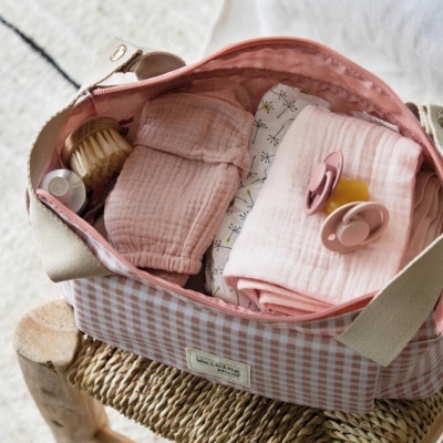 Saco de mão xadrez rosa e branco com artigos de bebé no interior