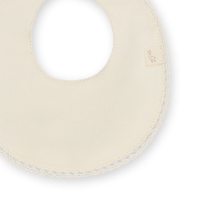 Babete redonda bege claro com acabamento rendado e etiqueta com desenho de ave