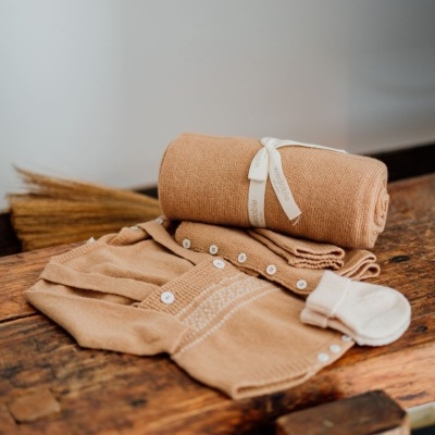 Conjunto de roupa de bebé bege em malha com manta enrolada e meias