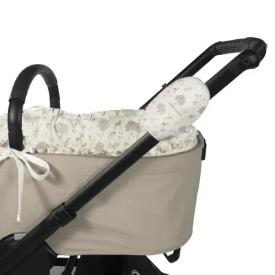 Carrinho de bebé bege com interior branco decorado e alça preta com espuma branca estampada