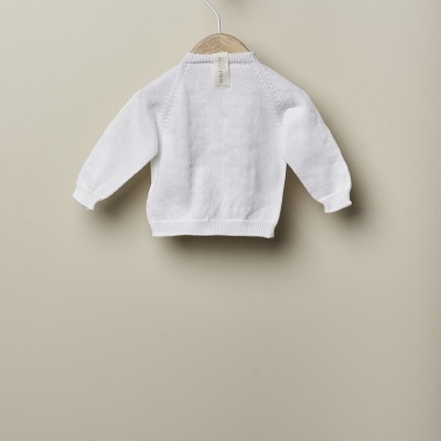 Camisola branca de malha pendurada num cabide de madeira