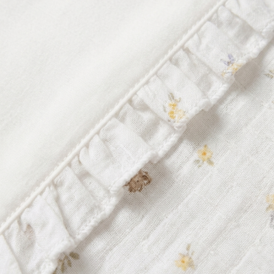 Tecido branco com padrão floral e babados bordados na borda.