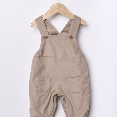 jardineiras de bebé bege em tecido algodão com bolsos e botões penduradas