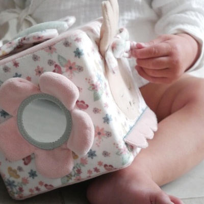 bebé a segurar cubo de tecido macio com padrão floral e flor com espelho