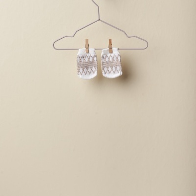 Par de peúgas brancas com padrão de losangos cinza penduradas em cabide