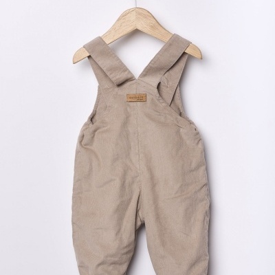 Macacão para bebé bege de veludo com alças largas num cabide de madeira