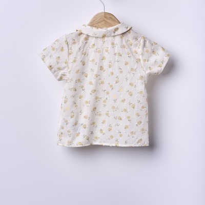 Camisola de criança branca com flores amarelas pendurada num cabide