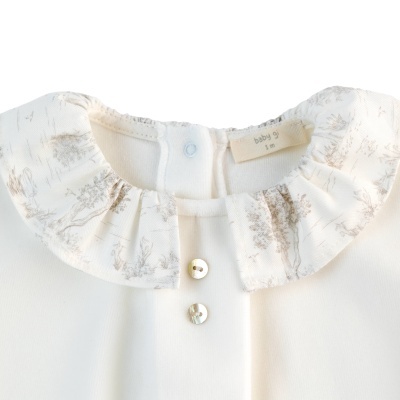 Blusa branca de bebé com gola floral cinzenta e botões brancos