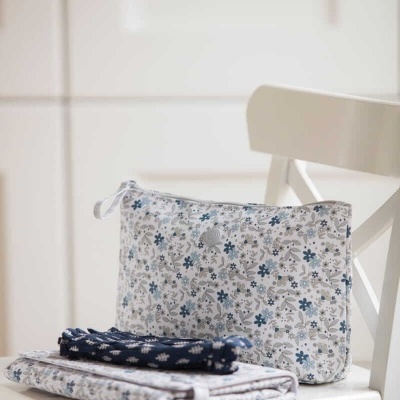 Bolsa, pano azul com flores brancas e toalha branca com flores azuis em cadeira branca