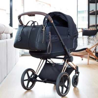 Carrinho de bebé preto com bolsa pendurada em sala moderna
