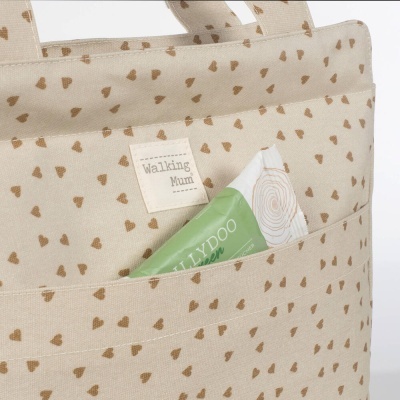 Saco bege com corações castanhos e etiqueta Walking Mum com tubo verde no bolso
