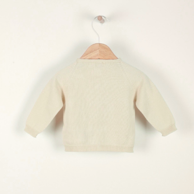 Camisola de malha creme para criança pendurada num cabide
