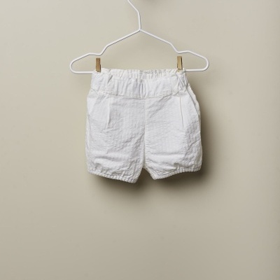 Calções de bebé brancos pendurados num cabide branco