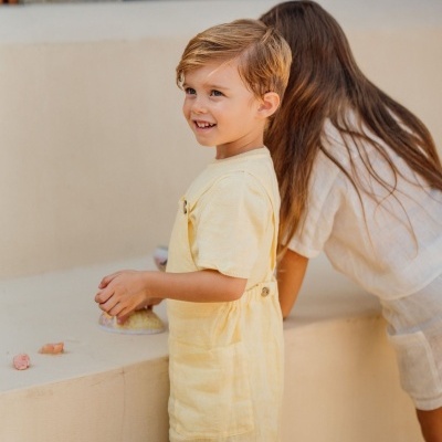 Criança com macacão amarelo e criança com vestido branco em espaço exterior