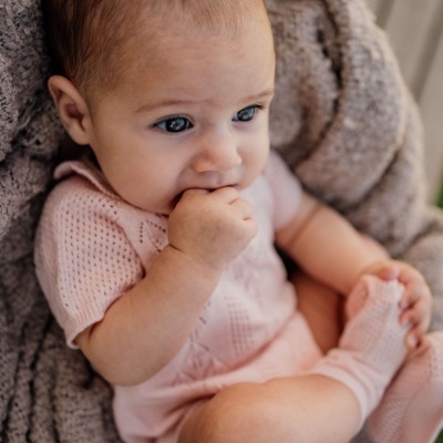 Bebé com roupa rosa e manta cinzenta