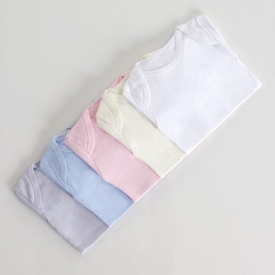 Bodies de bebé dobrados em várias cores sobre fundo branco