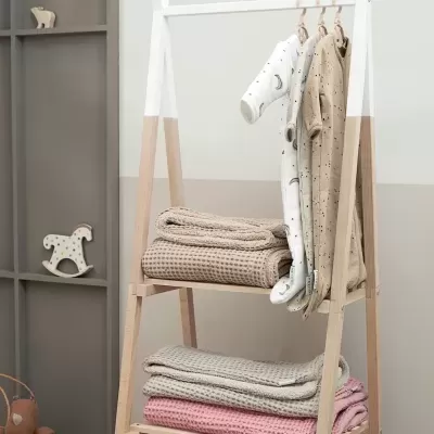 Estante de madeira com roupa de bebé e mantas coloridas
