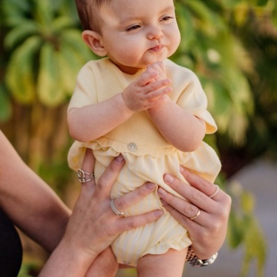 Bebé com roupa amarela clara em ambiente exterior com vegetação
