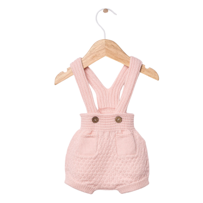 Macacão de bebé cor de rosa em malha com botões e bolsos pendurado num cabide