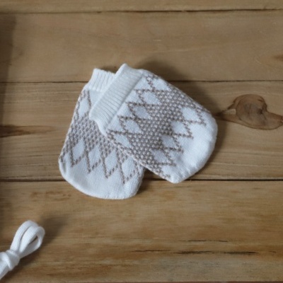 Meias de bebé brancas com padrão de losangos cinza sobre superfície de madeira